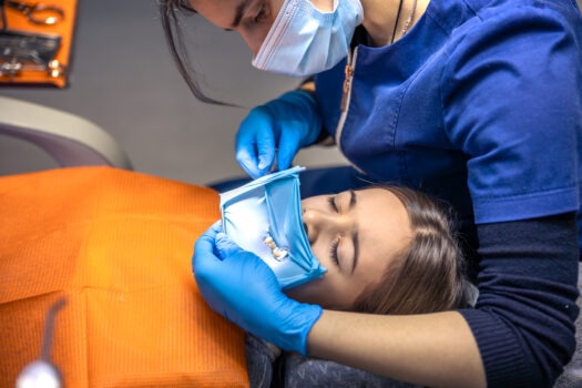 The dentist treats the child's tooth using a rubber dam. Close-up of tooth treatment.